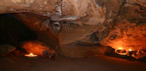 Fire glowing inside a natural rock shelter at Awelani